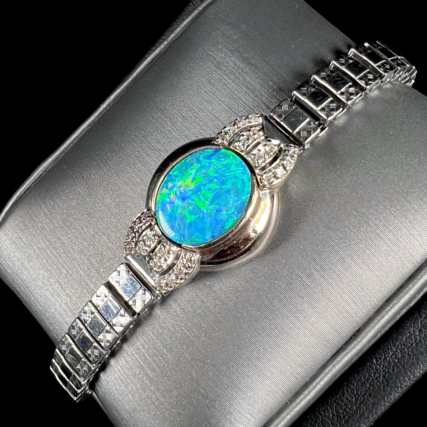 A ladies' art deco style white gold and stainless steel bracelet set with a natural black opal doublet and diamonds.