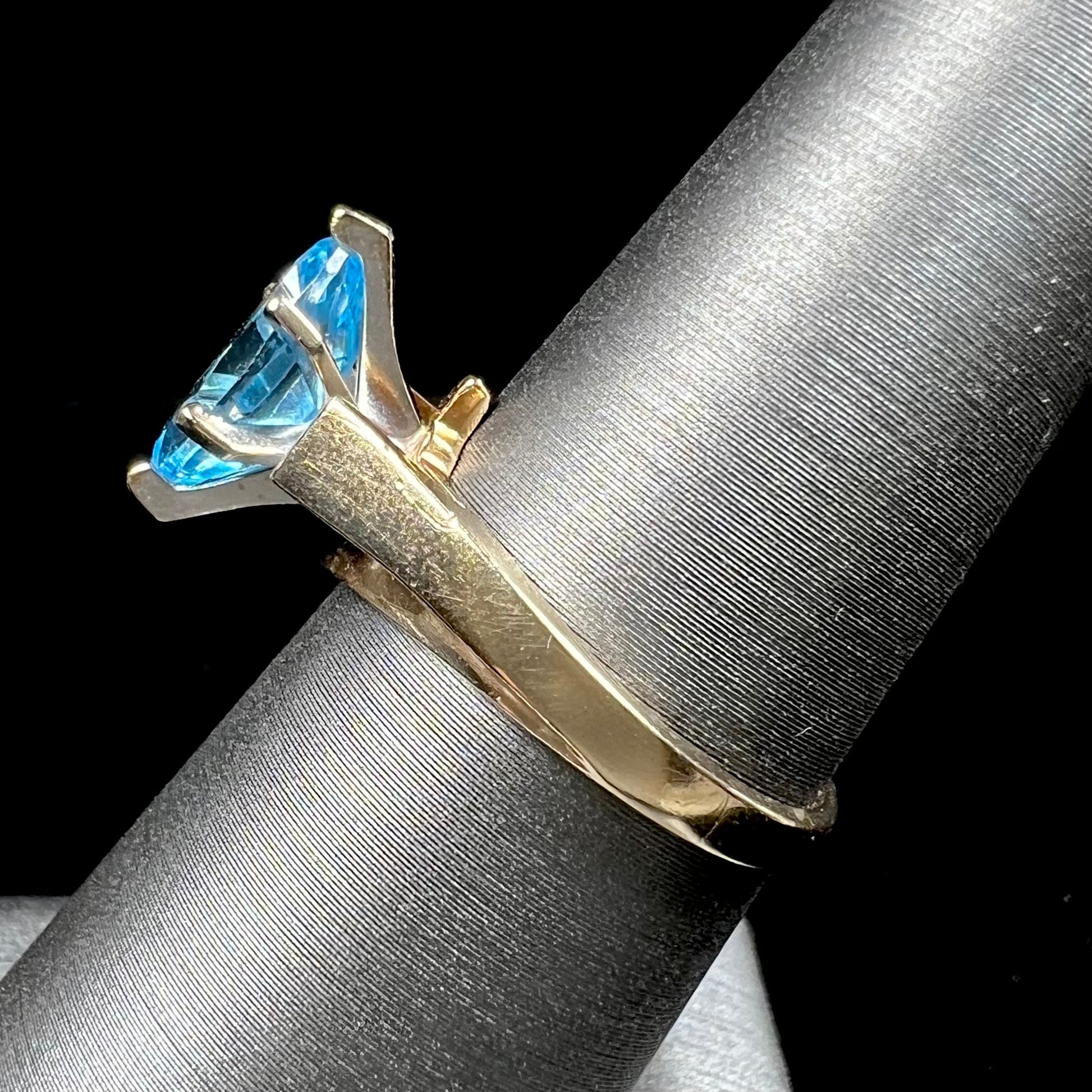 A ladies' estate yellow gold ring, prong set with a marquise cut blue topaz stone.  There are scratches on the shank.
