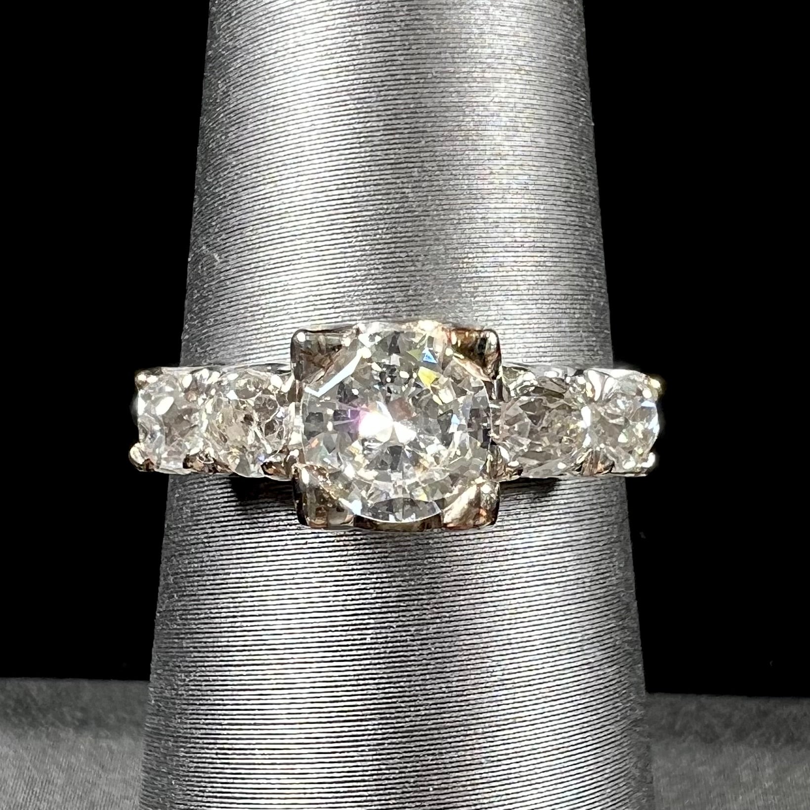A ladies' 1800's antique white gold diamond ring.  The center stone is an Early American Cut diamond, and the accent stones are Old Mine Cut diamonds.