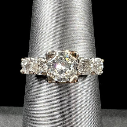 A ladies' 1800's antique white gold diamond ring.  The center stone is an Early American Cut diamond, and the accent stones are Old Mine Cut diamonds.