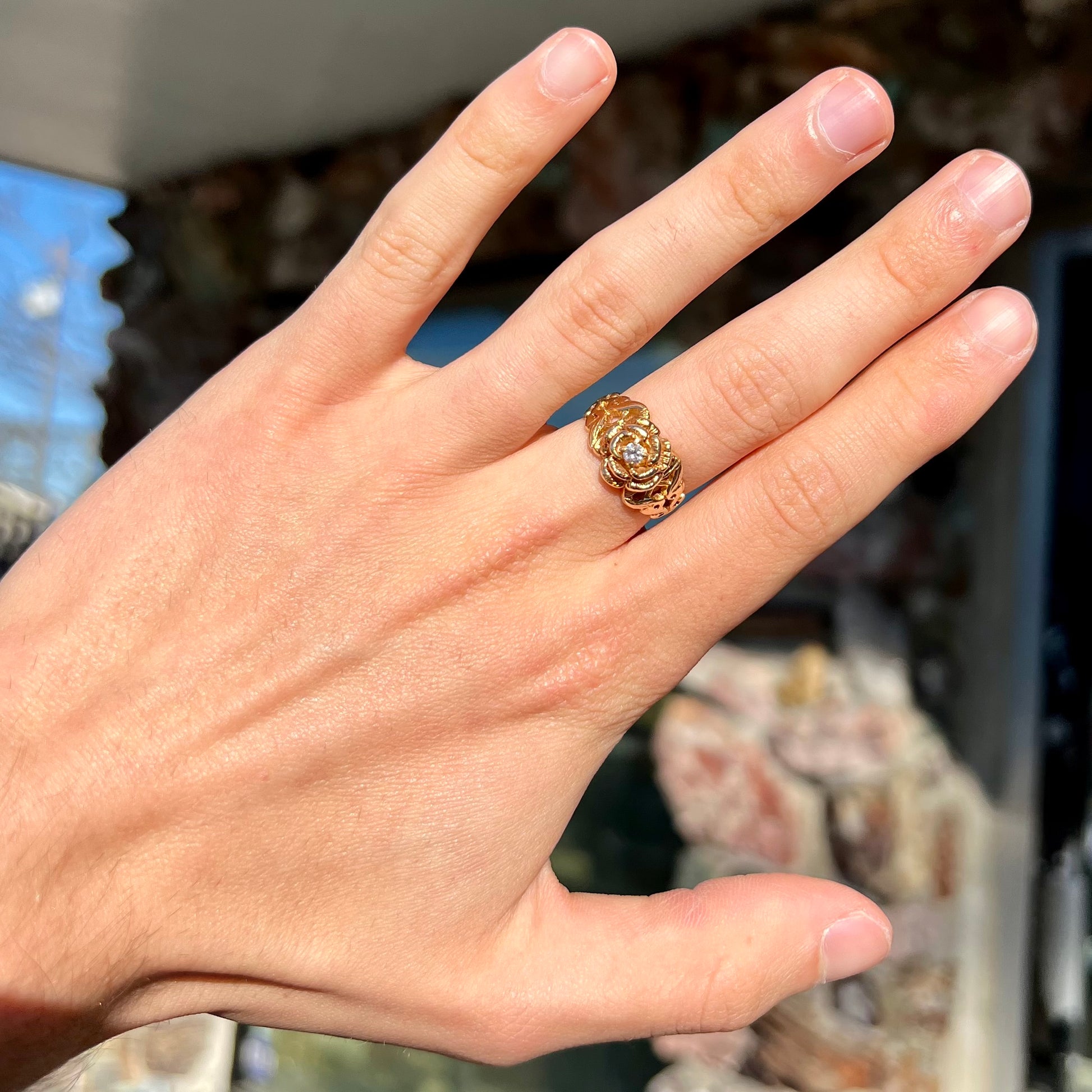 A ladies' yellow gold rose style ring set with a natural 0.10ct diamond.