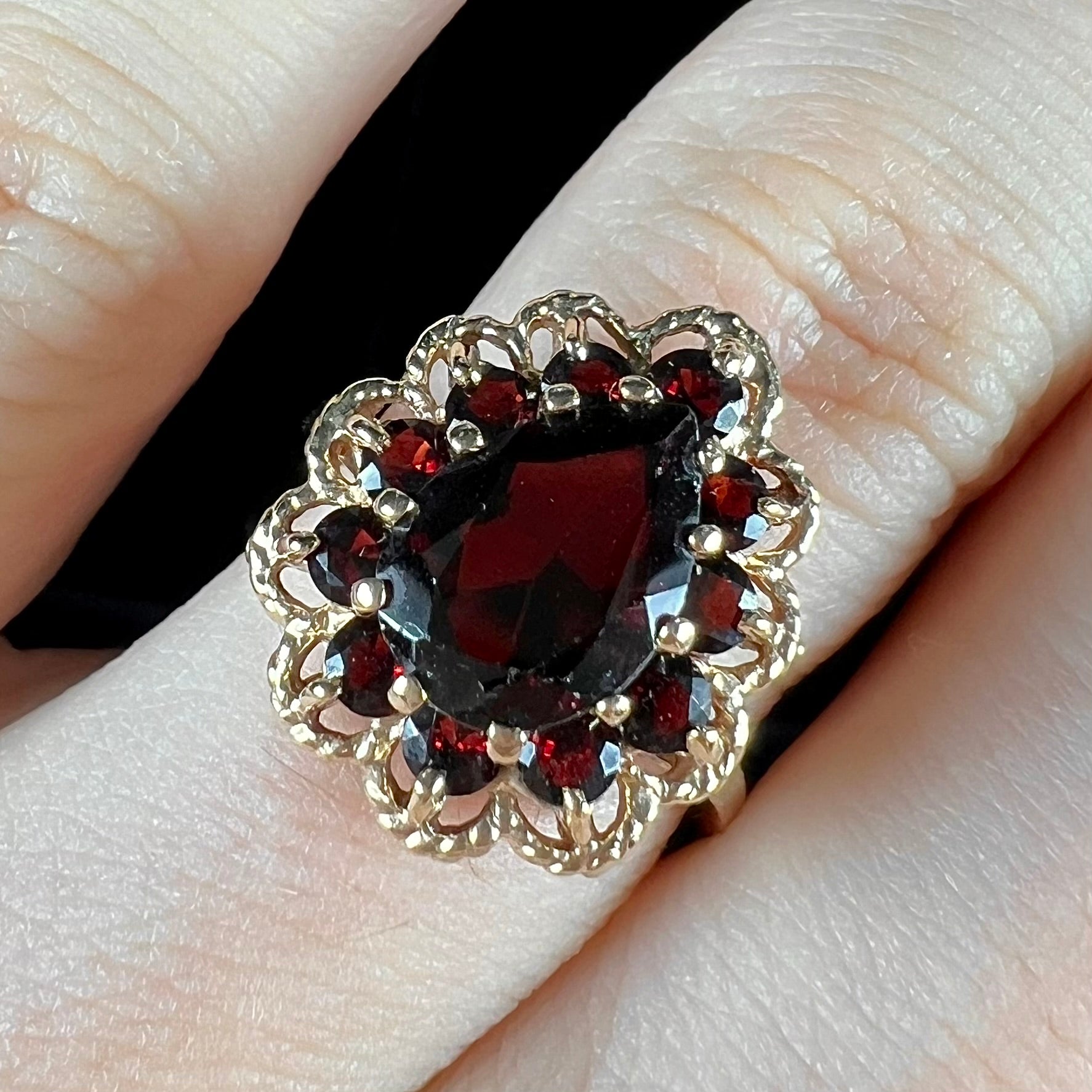 A vintage, 1940's style yellow gold ring set with a pear shaped almandine garnet.  A halo of round garnets surround the center stone.