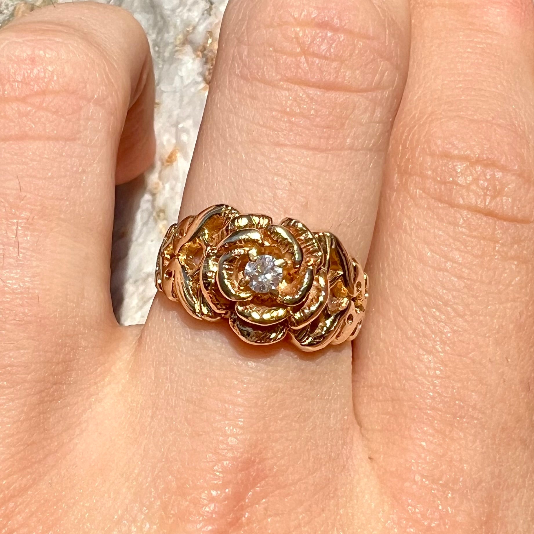 A ladies' yellow gold rose style ring set with a natural 0.10ct diamond.