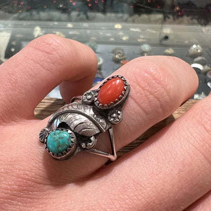 A vintage sterling silver Navajo style ring set with turquoise and coral stones and a feather design.