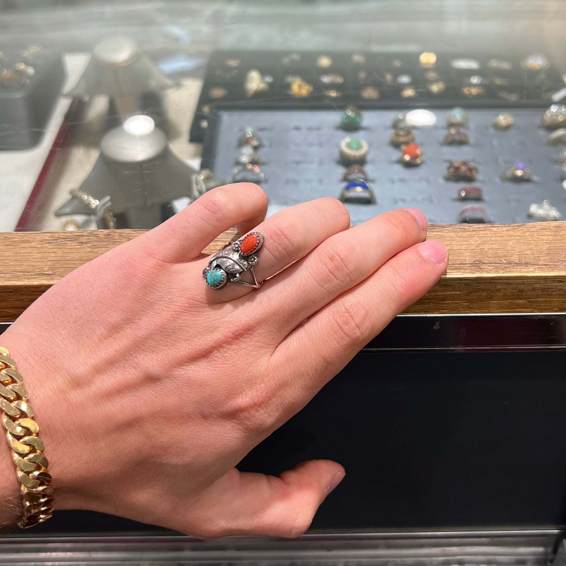 A vintage sterling silver Navajo style ring set with turquoise and coral stones and a feather design.
