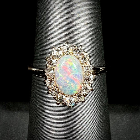 An 18k yellow gold Edwardian style opal and diamond halo ring.  The diamonds are Old European Cut, and the opal shines reddish pink colors.