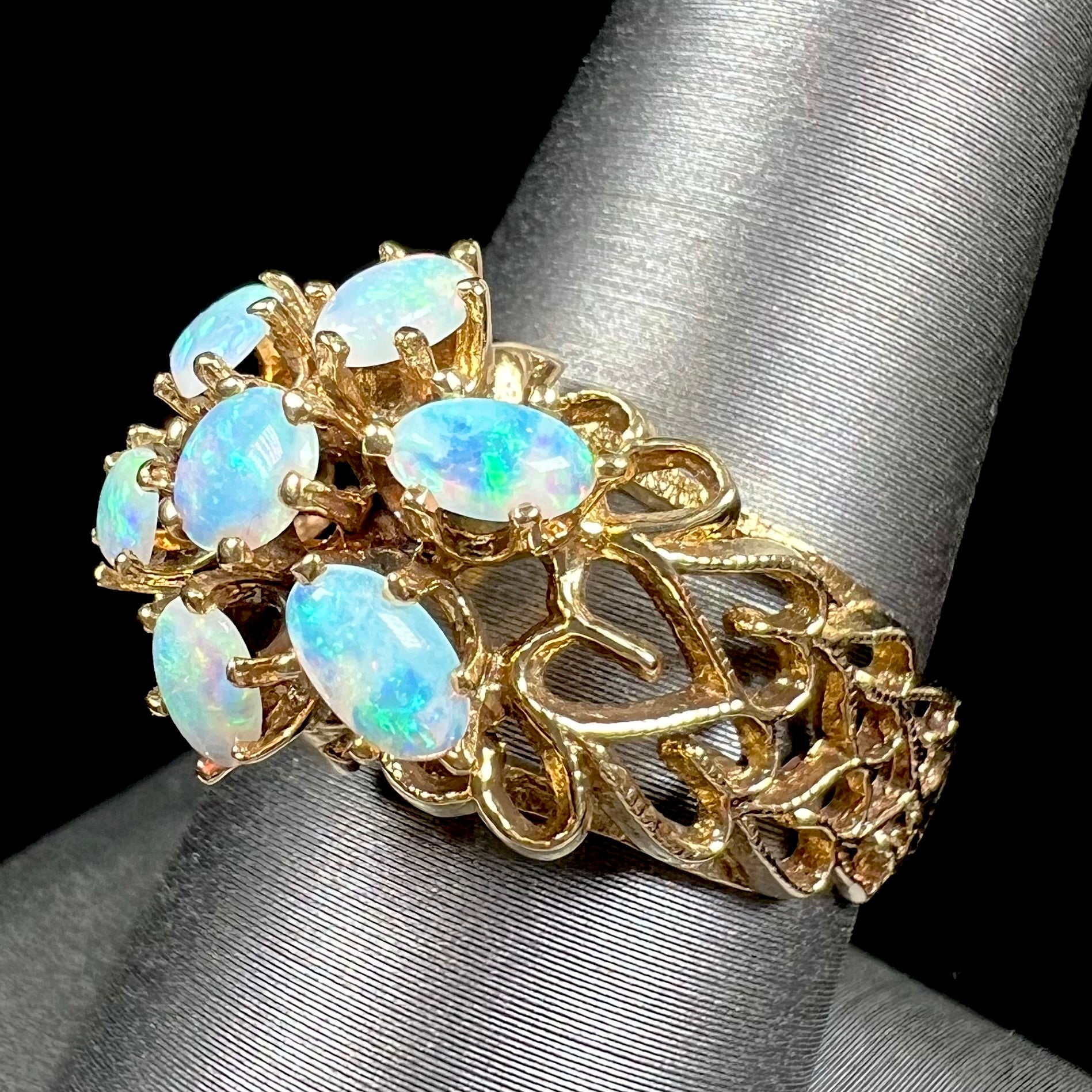 A vintage, 1950's style opal cluster ring cast in yellow gold with a heart shaped filigree design.