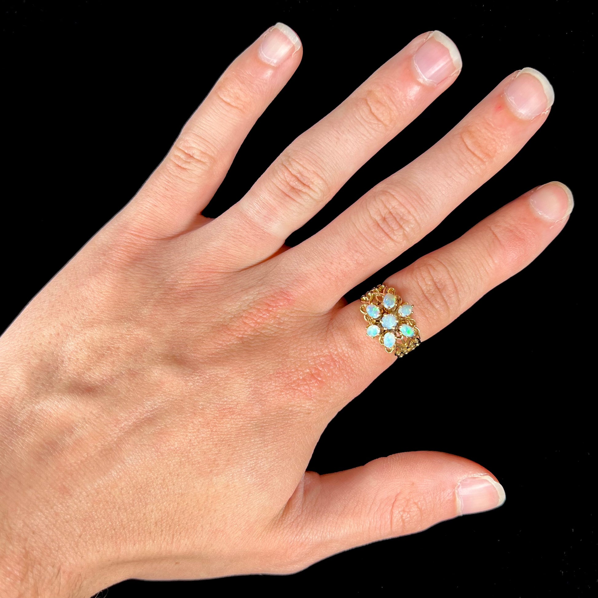 A vintage, 1950's style opal cluster ring cast in yellow gold with a heart shaped filigree design.