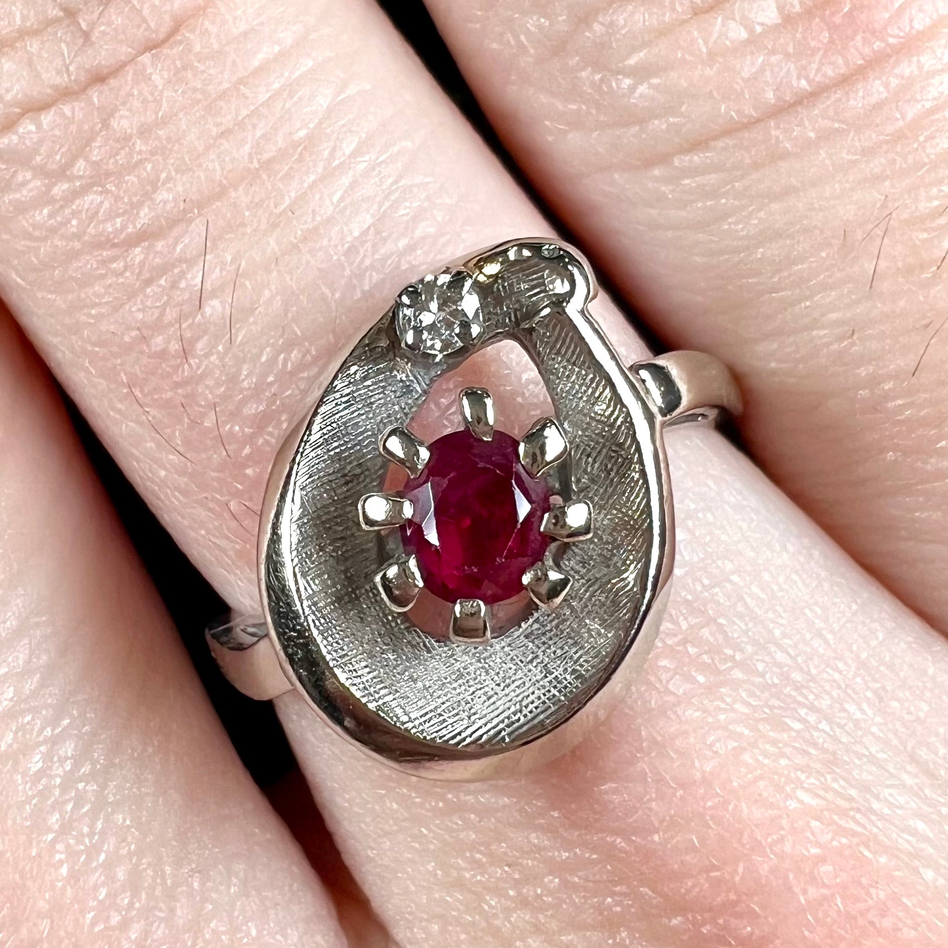 A ladies' estate white gold ruby ring set with a diamond accent stone.