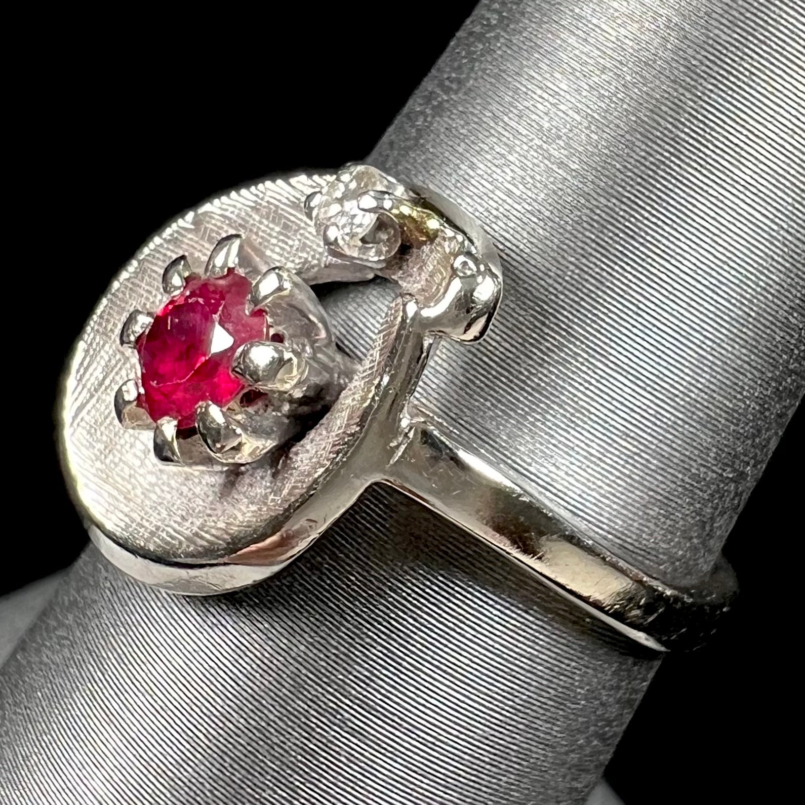 A ladies' estate white gold ruby ring set with a diamond accent stone.