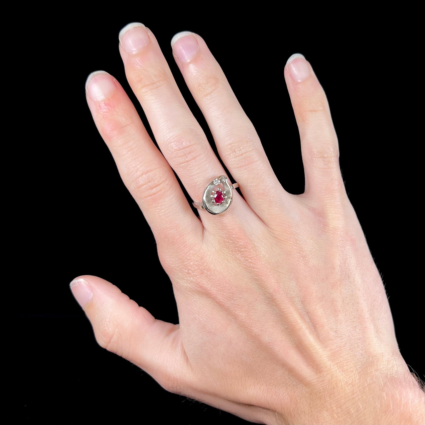 A ladies' estate white gold ruby ring set with a diamond accent stone.