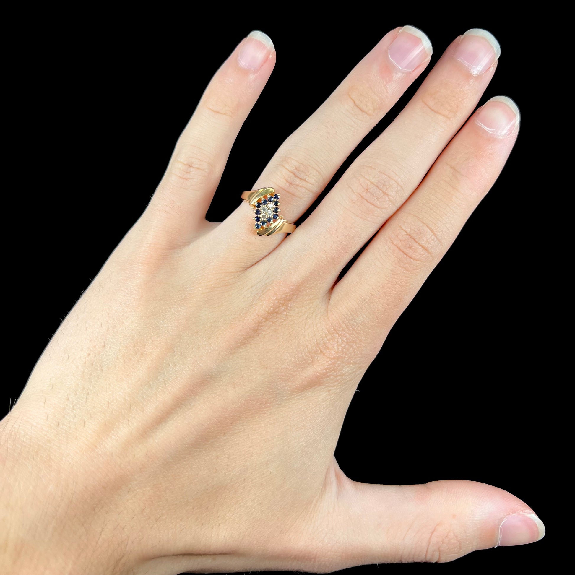 An estate, yellow gold ladies' cluster ring mounted with four round diamonds and twelve round blue sapphires.