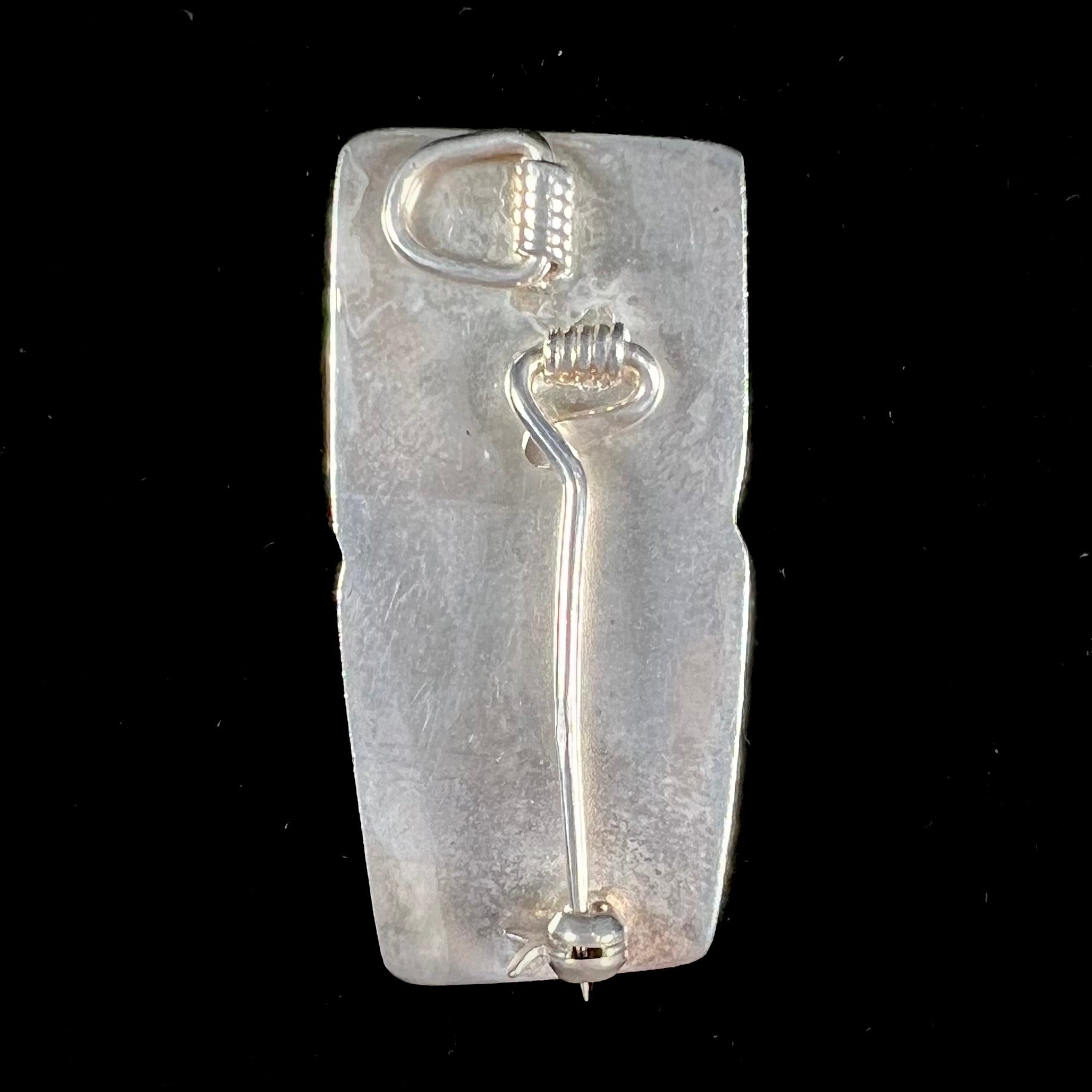 A sterling silver pendant brooch set with a red orange amber and a yellow sun-spangled amber.