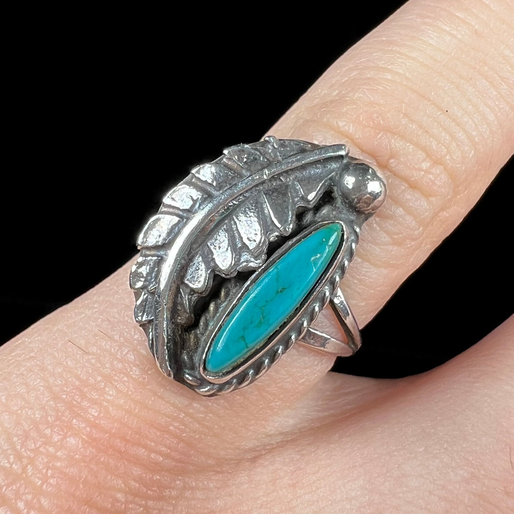 A ladies' sterling silver feather style ring set with a marquise cut turquoise stone.