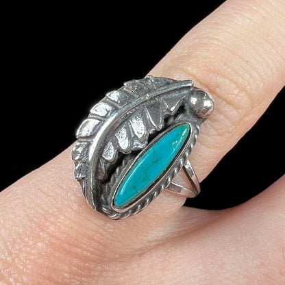 A ladies' sterling silver feather style ring set with a marquise cut turquoise stone.