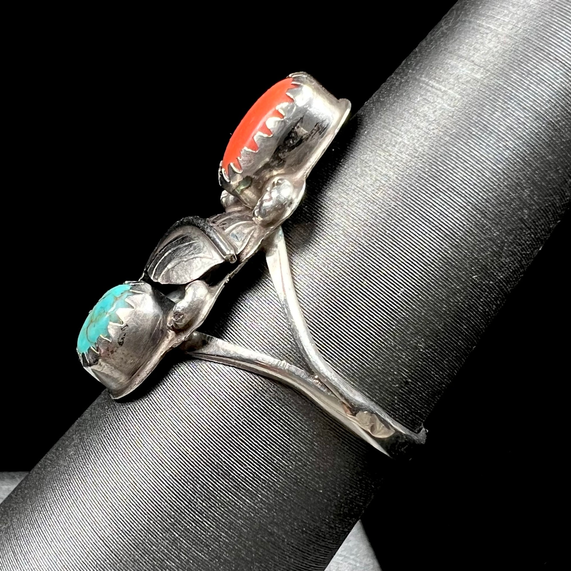 A vintage sterling silver Navajo style ring set with turquoise and coral stones and a feather design.