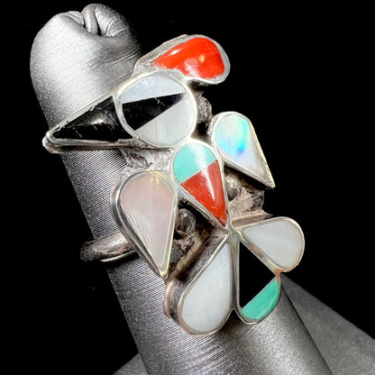 A vintage, sterling silver Zuni thunderbird ring inlaid with turquoise, mother of pearl, onyx, and coral stones.