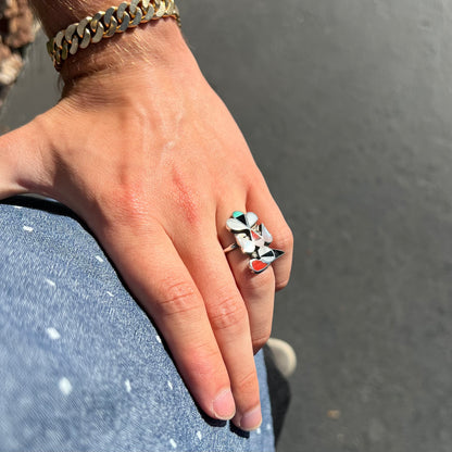 A vintage, sterling silver Zuni thunderbird ring inlaid with turquoise, mother of pearl, onyx, and coral stones.