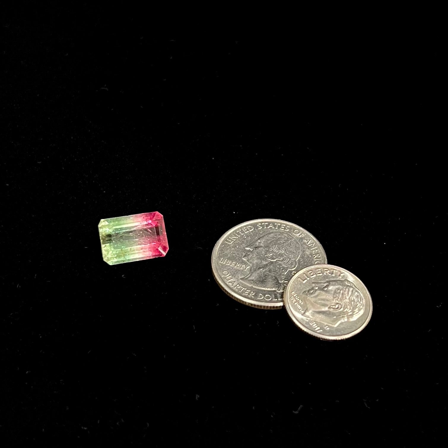 A loose watermelon tourmaline gemstone.  The stone is emerald cut and fades from hot pink to green.