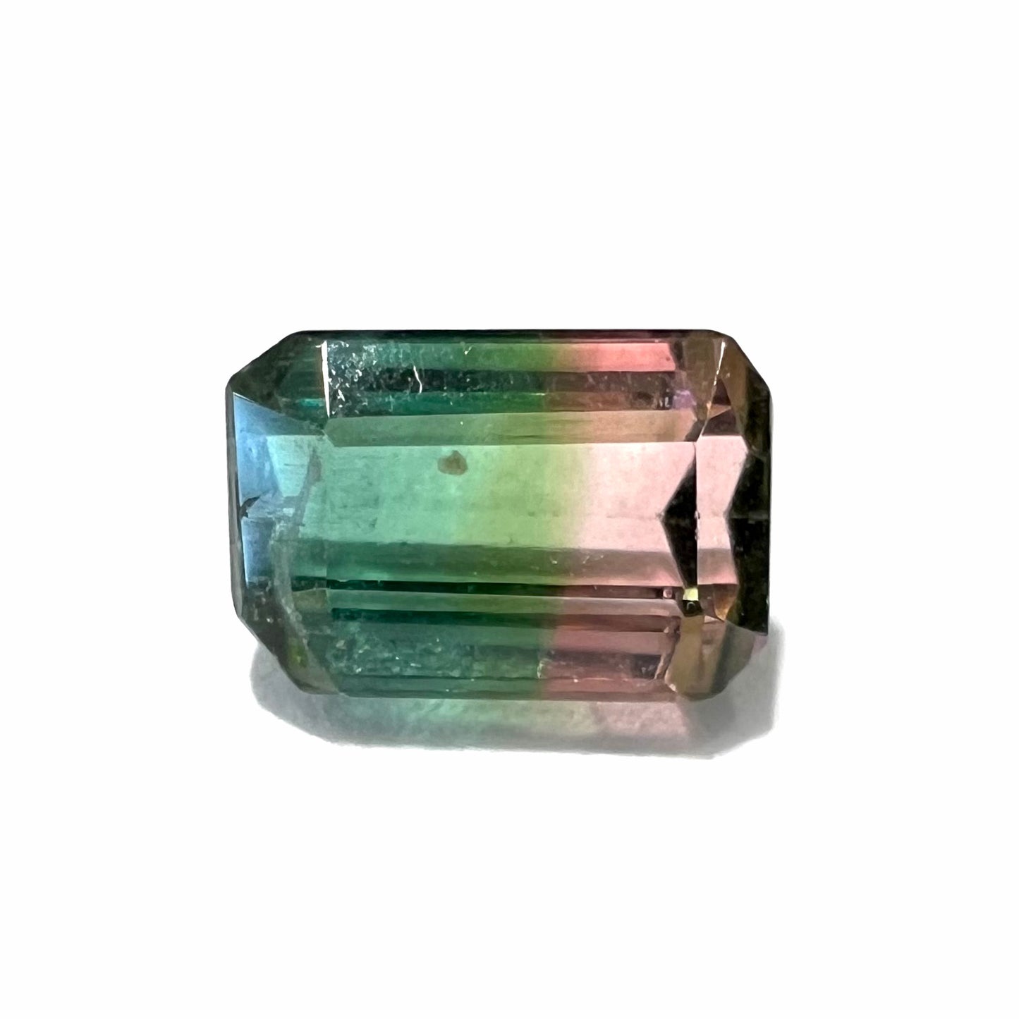 A loose, emerald cut tricolor watermelon tourmaline stone.  Colors displayed in the stone are green, blue, and pink.