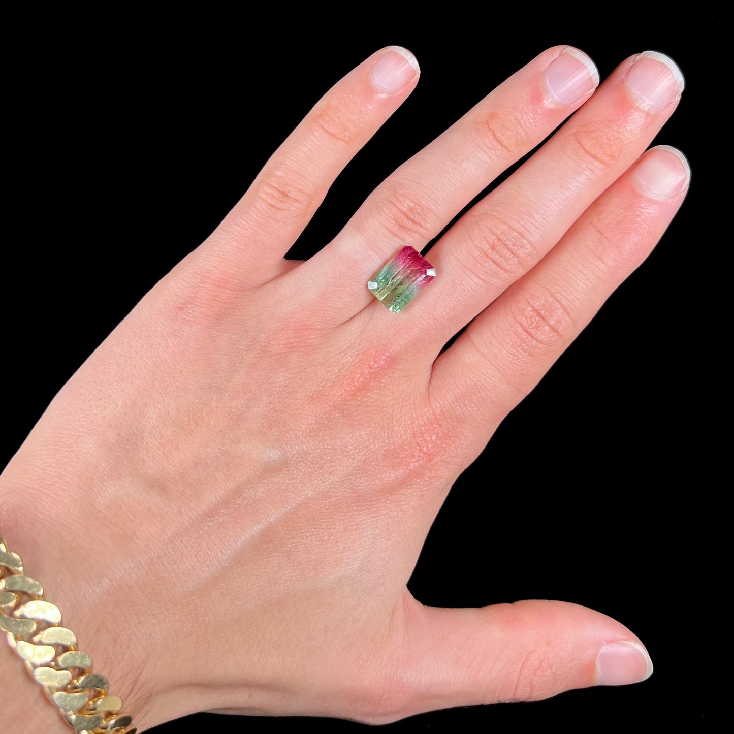 A loose watermelon tourmaline gemstone.  The stone is emerald cut and fades from hot pink to green.