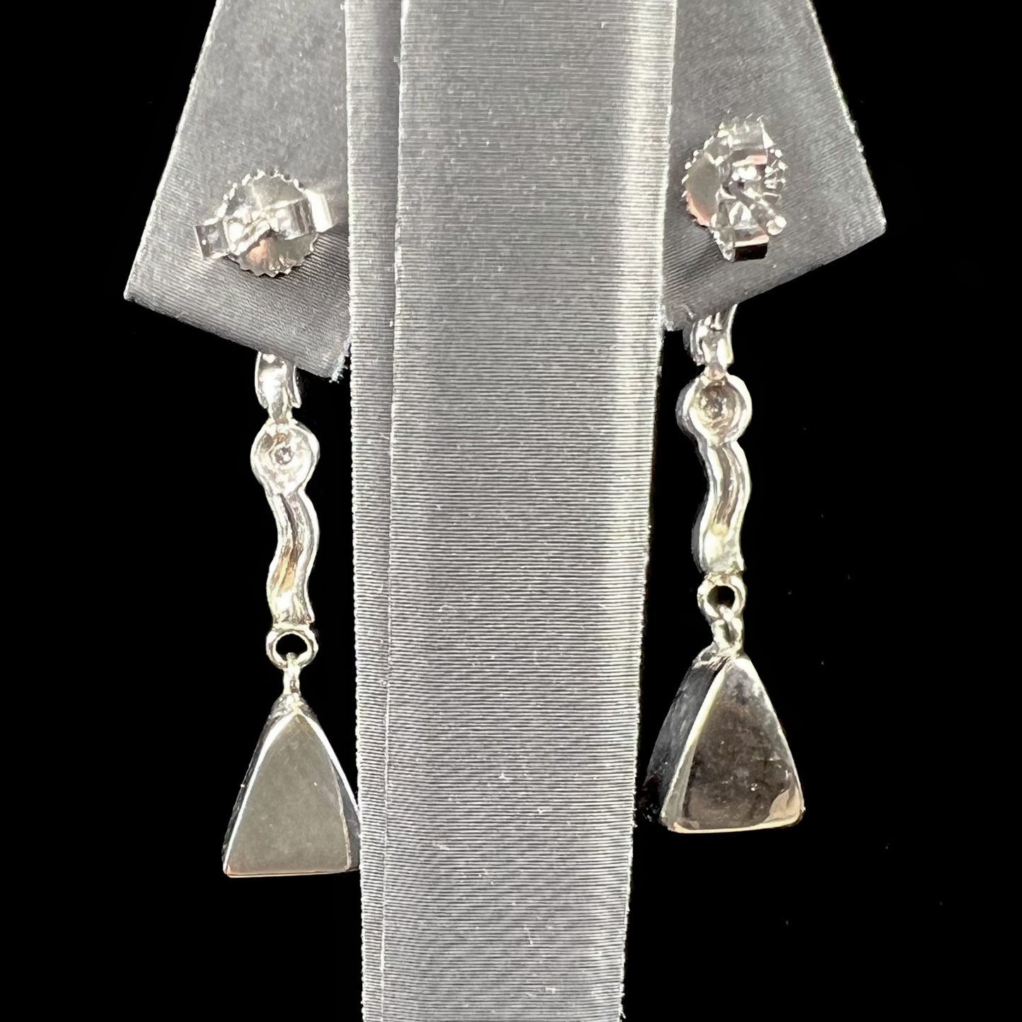 A pair of white gold earrings set with triangle cut natural black opals and round diamond accents.