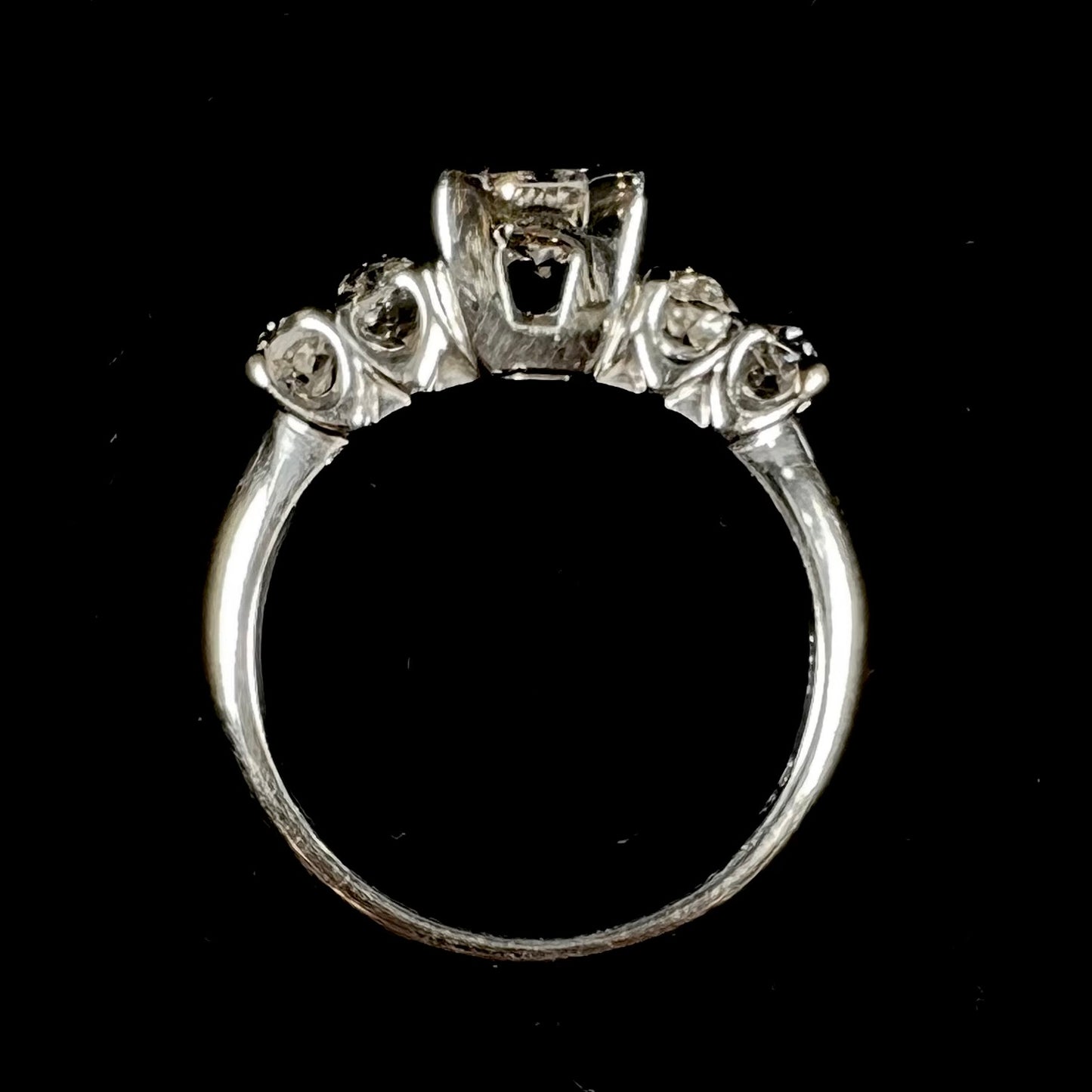 A ladies' 1800's antique white gold diamond ring.  The center stone is an Early American Cut diamond, and the accent stones are Old Mine Cut diamonds.
