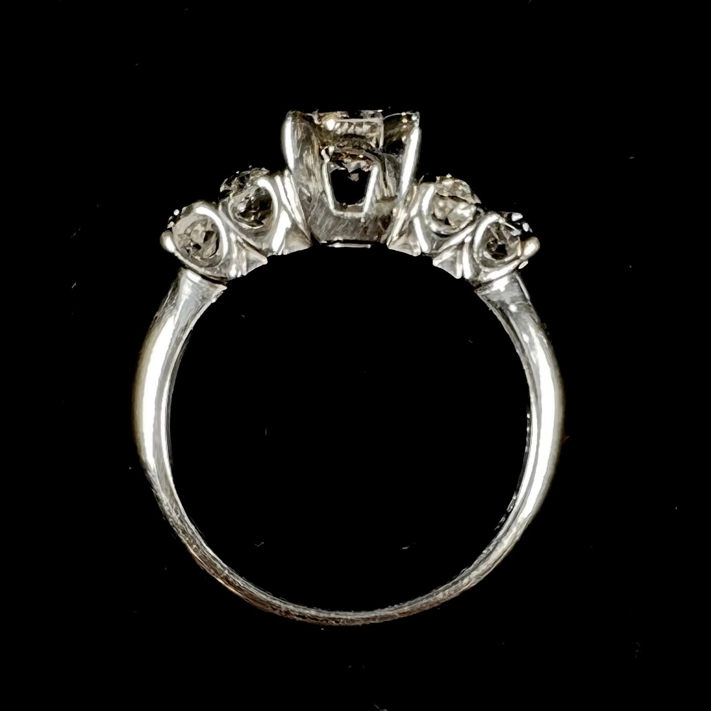 A ladies' 1800's antique white gold diamond ring.  The center stone is an Early American Cut diamond, and the accent stones are Old Mine Cut diamonds.