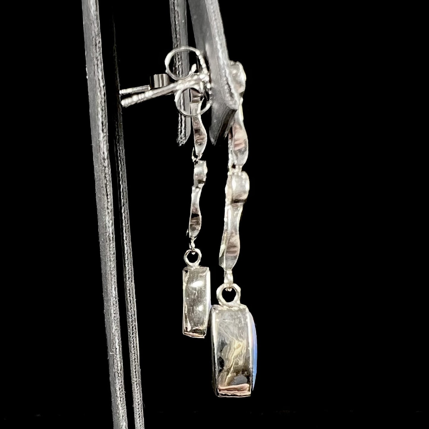 A pair of white gold earrings set with triangle cut natural black opals and round diamond accents.