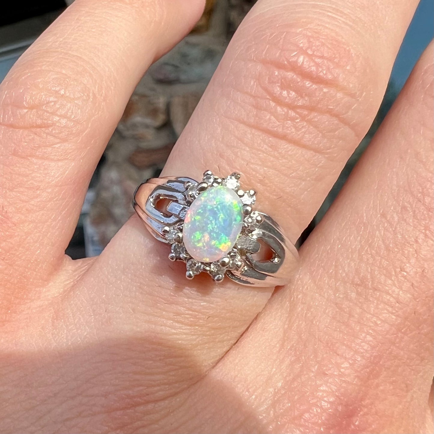 A ladies' white gold ring set with a halo of diamonds and an oval cabochon cut Australian opal.
