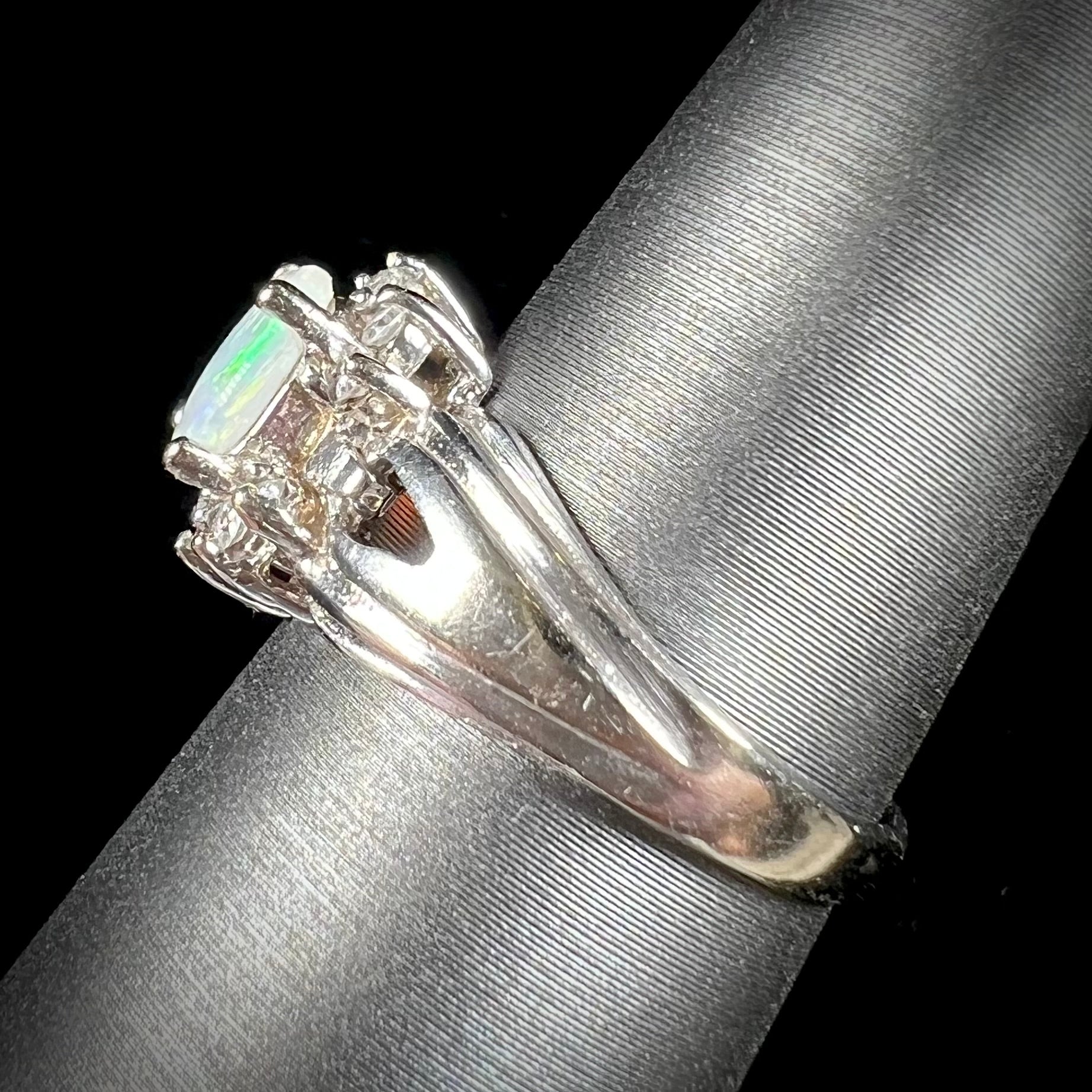 A ladies' white gold ring set with a halo of diamonds and an oval cabochon cut Australian opal.