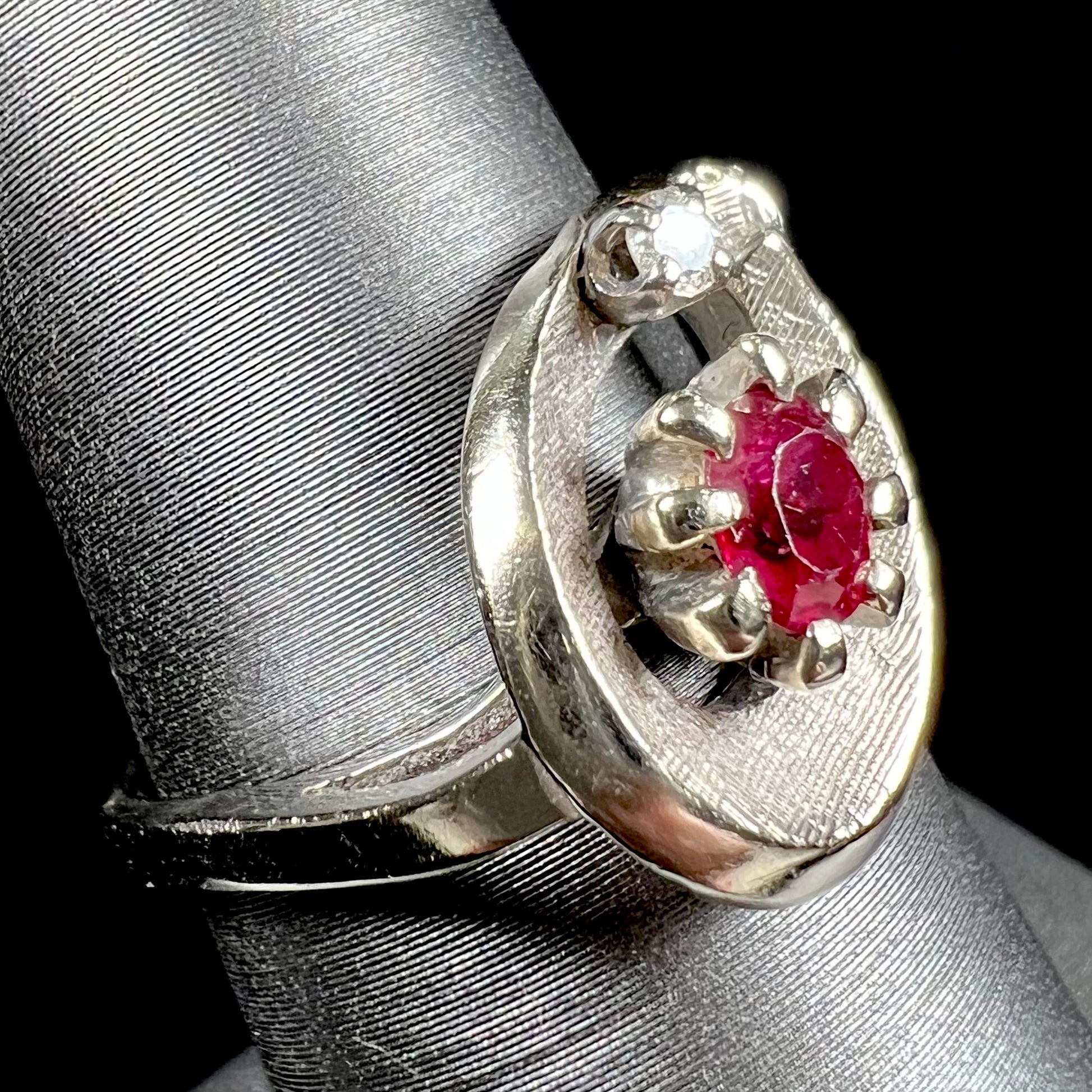 A ladies' estate white gold ruby ring set with a diamond accent stone.