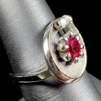 A ladies' estate white gold ruby ring set with a diamond accent stone.