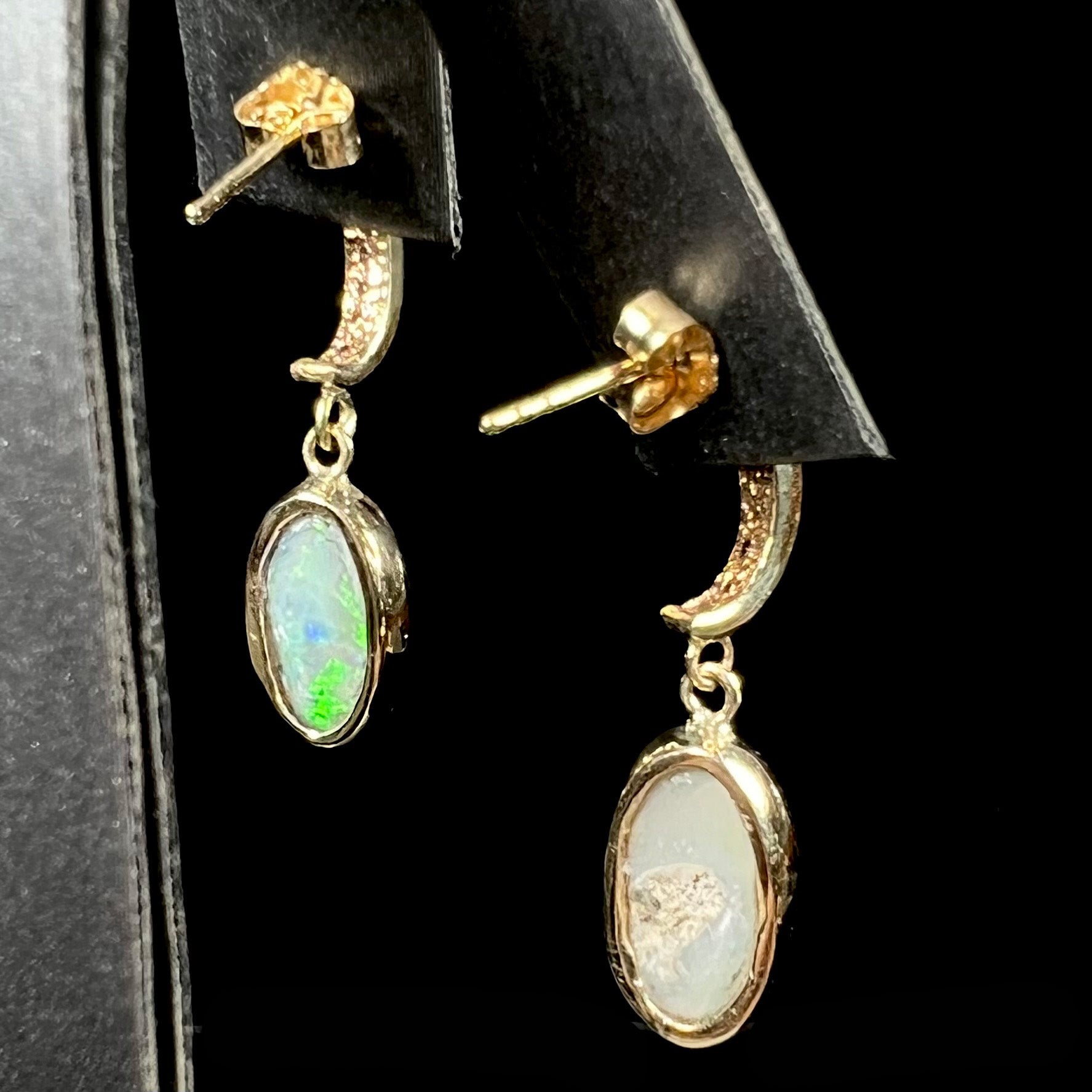 A pari of yellow gold dangle earrings set with natural white crystal opals and diamond accents.