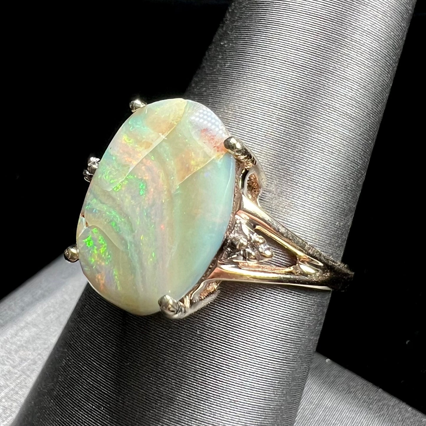 A ladies' Australian boulder opal ring set in yellow gold with diamond accents.  The opal shimmers green and pink and has fissure inclusions.