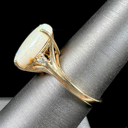 A ladies' yellow gold ring set with two diamonds and an oval cut natural opal stone.