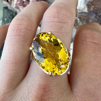 An 18 karat yellow gold solitaire cocktail ring set with a faceted oval cut golden beryl gemstone.