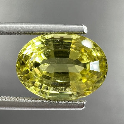 A loose, oval cut greenish yellow chrysoberyl stone.