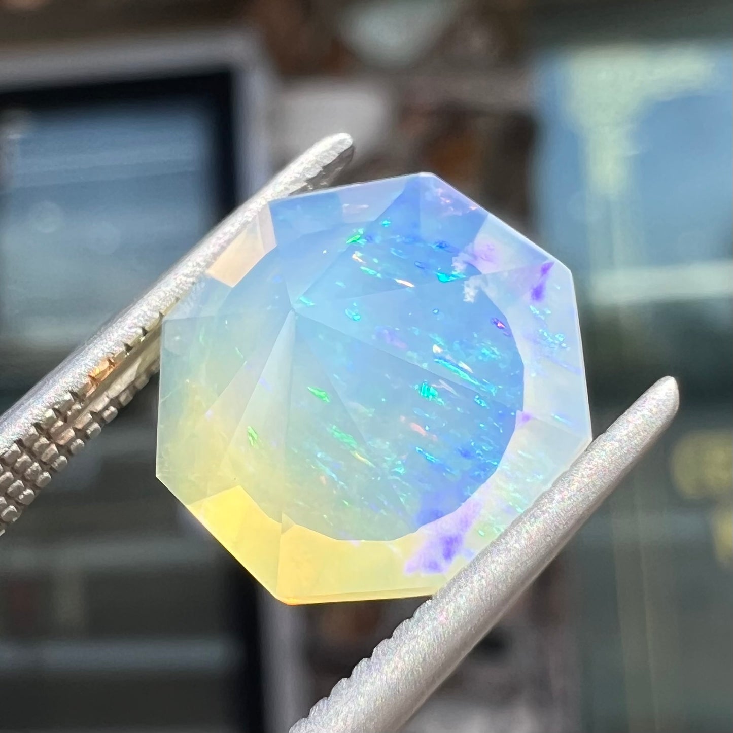 A loose, faceted octagon cut Mexican fire opal gemstone.  The stone is a light yellow color with blue and green fire.