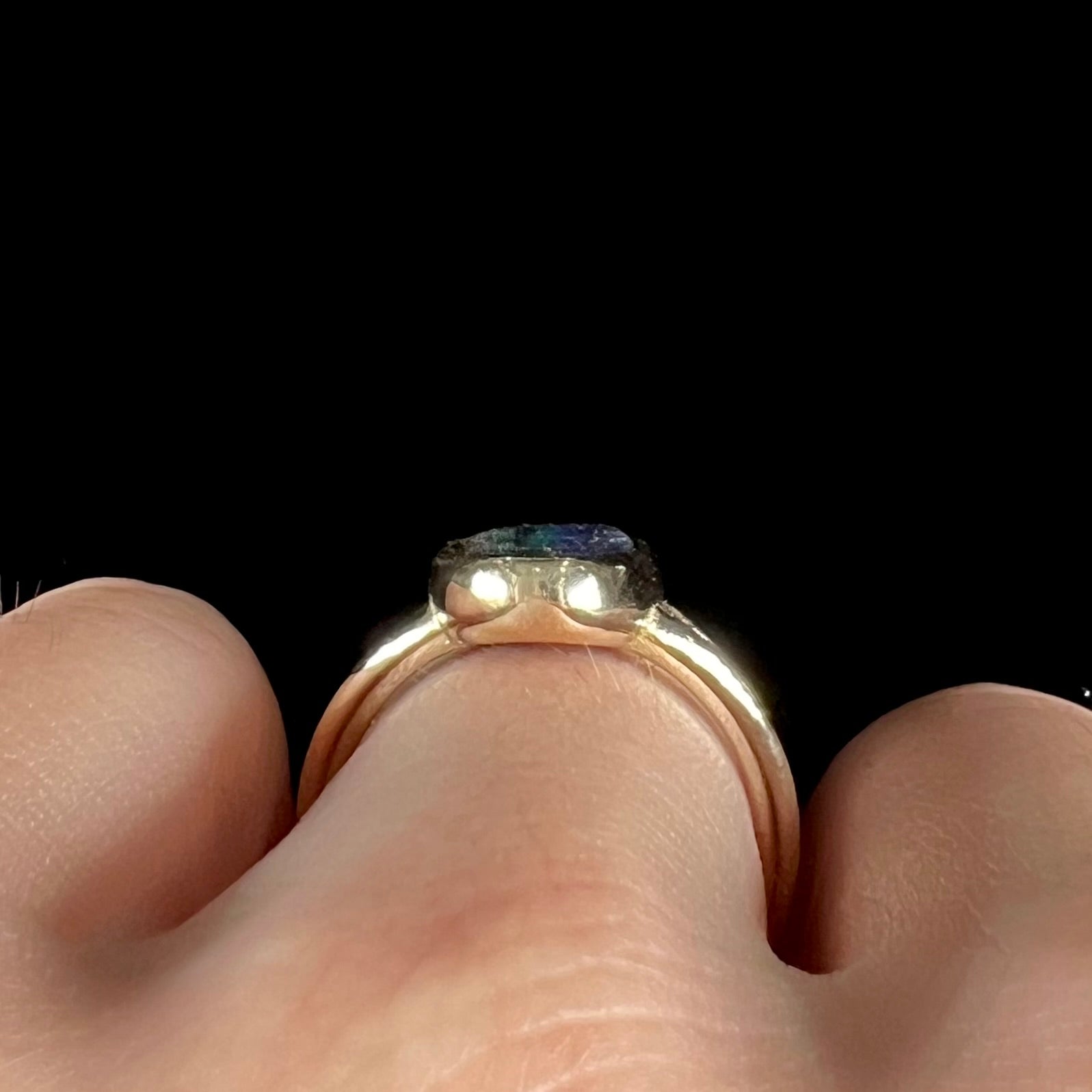 A ladies' yellow gold split shank solitaire ring set with a natural Australian black boulder opal.