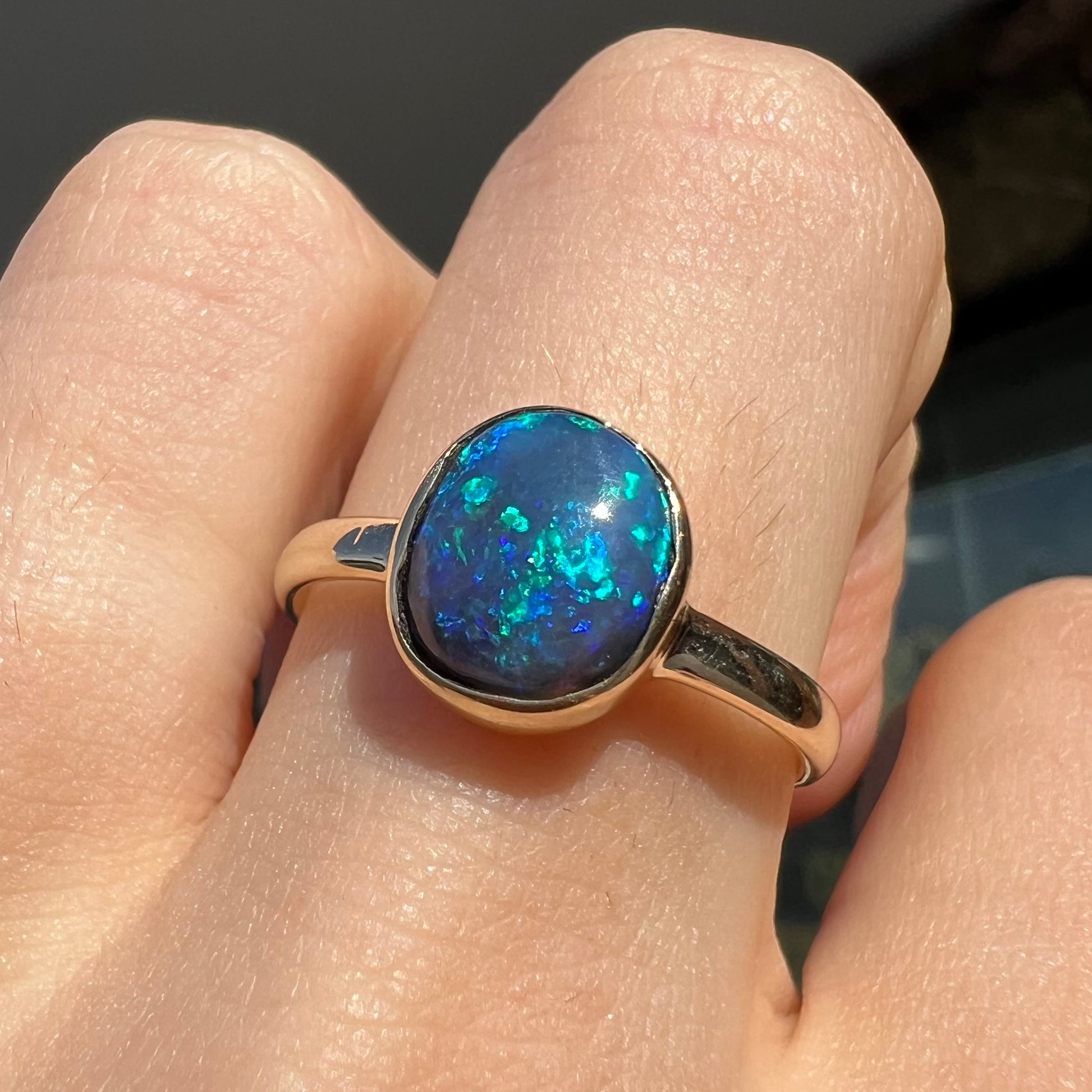 A ladies' natural black crystal opal solitaire ring handmade in 14 karat yellow gold.