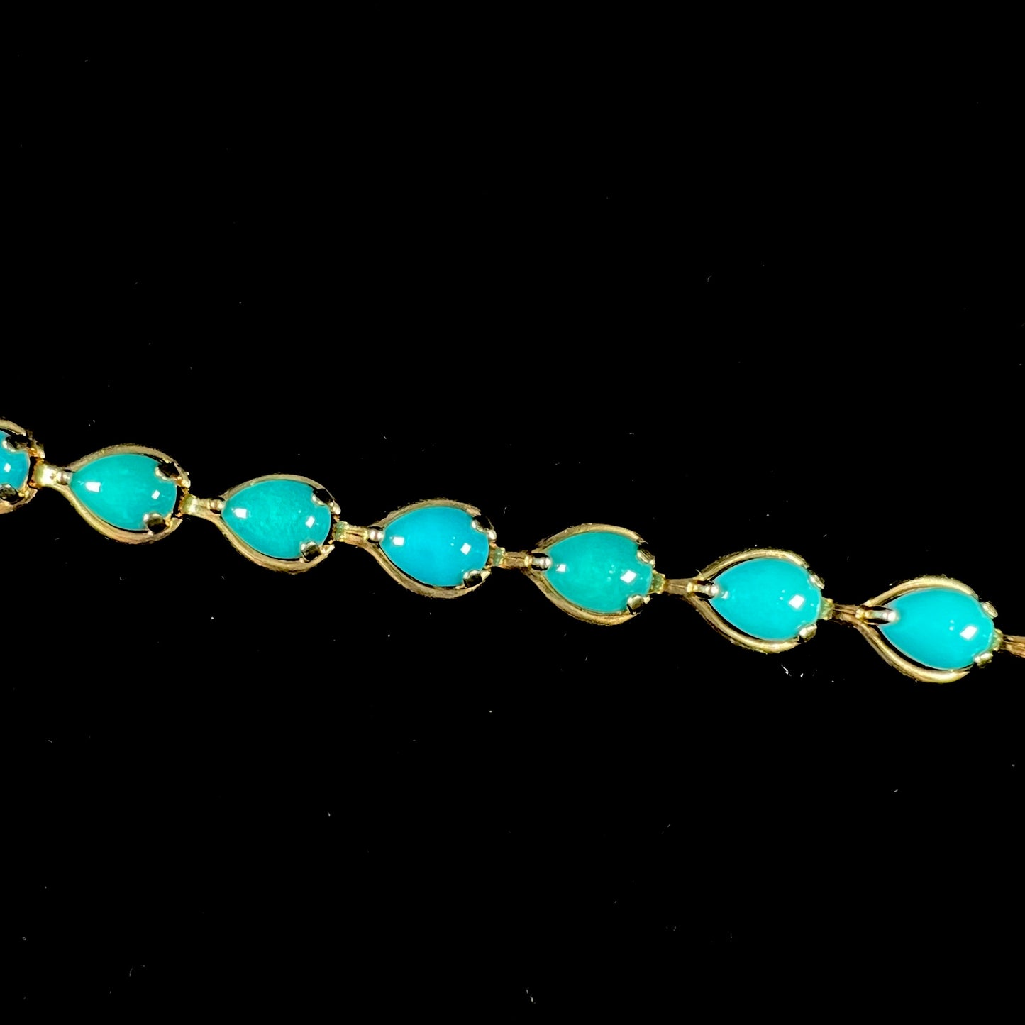 A ladies' yellow gold tennis style bracelet set with pear cabochon shaped natural Sleeping Beauty turquoise stones.