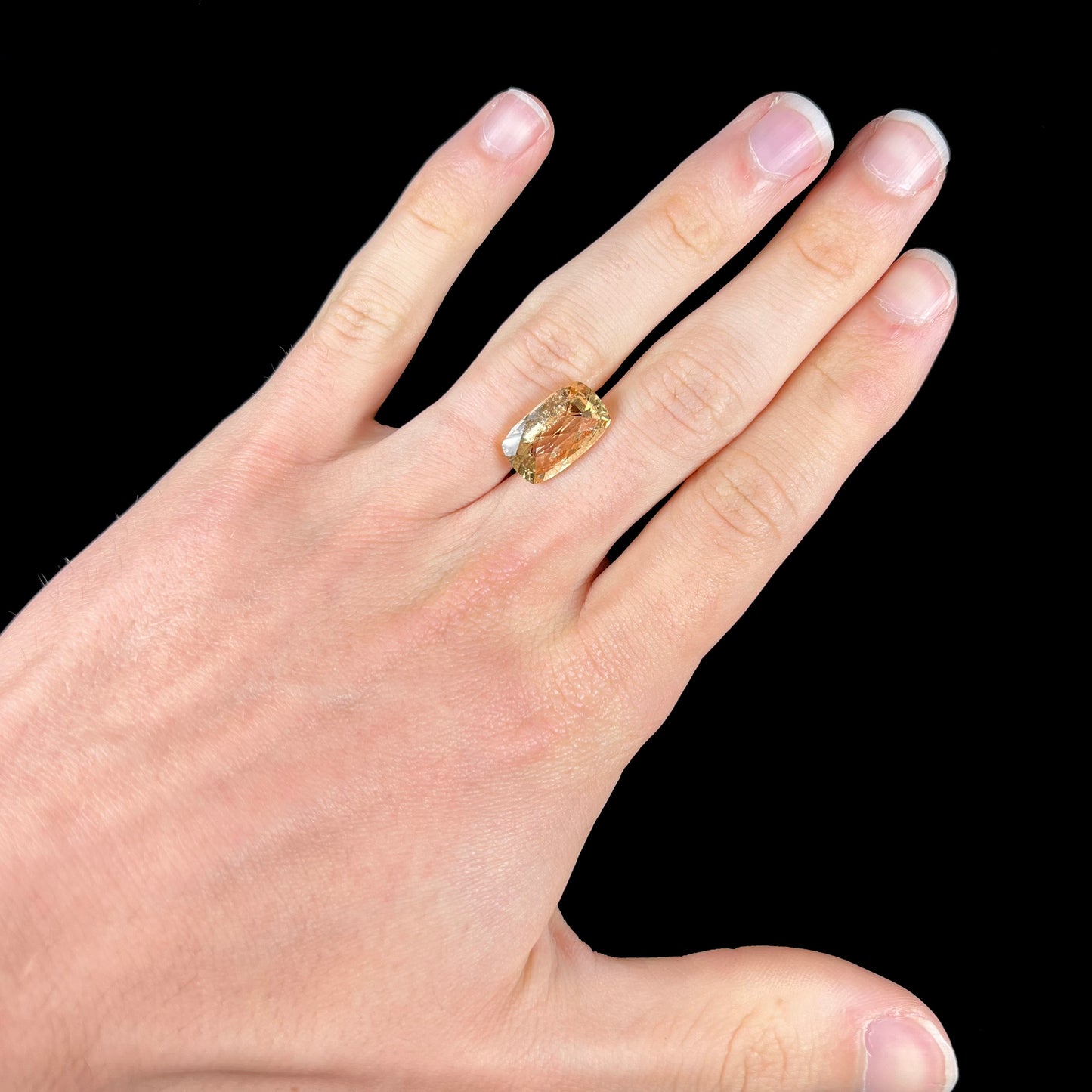 A loose, checkerboard cushion cut golden topaz gemstone.  The stone is a yellow color.