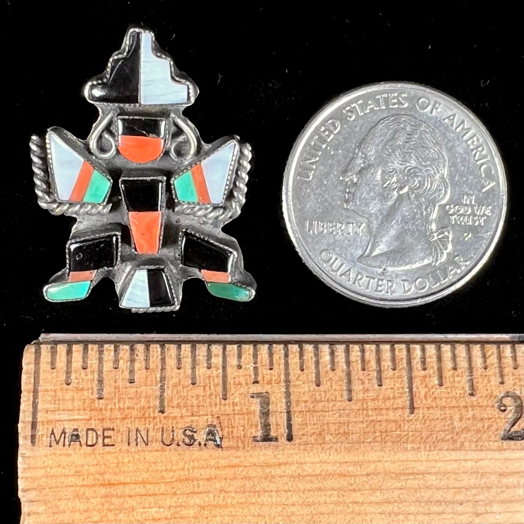 A sterling silver brooch depicting a Zuni Indian knifewing dancer, inlaid with jet, turquoise, coral, and mother of pearl.