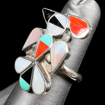 A vintage, sterling silver Zuni thunderbird ring inlaid with turquoise, mother of pearl, onyx, and coral stones.