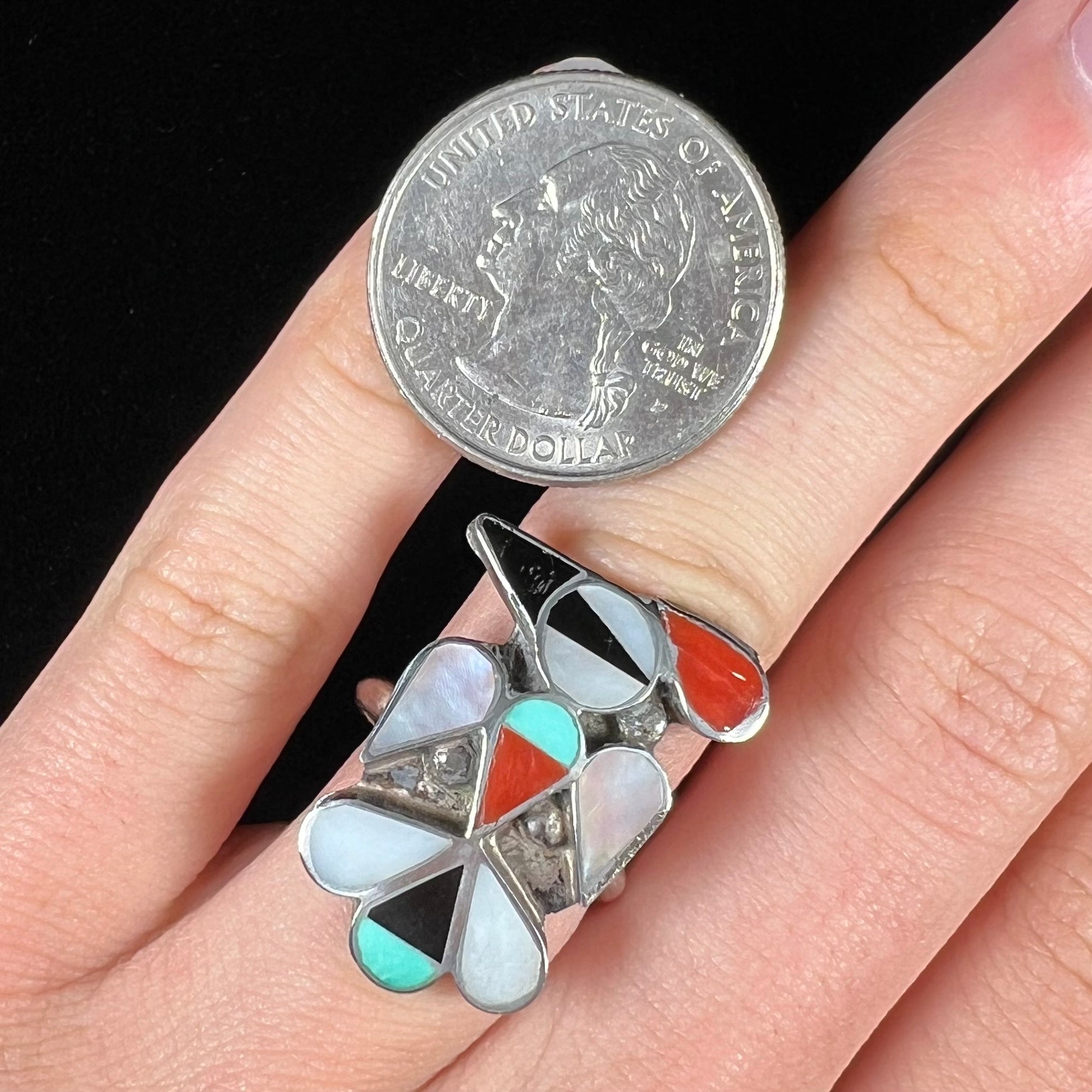 A vintage, sterling silver Zuni thunderbird ring inlaid with turquoise, mother of pearl, onyx, and coral stones.