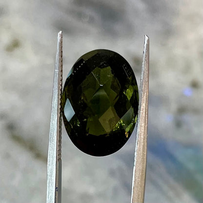 A loose faceted oval checkerboard cut moldavite stone.