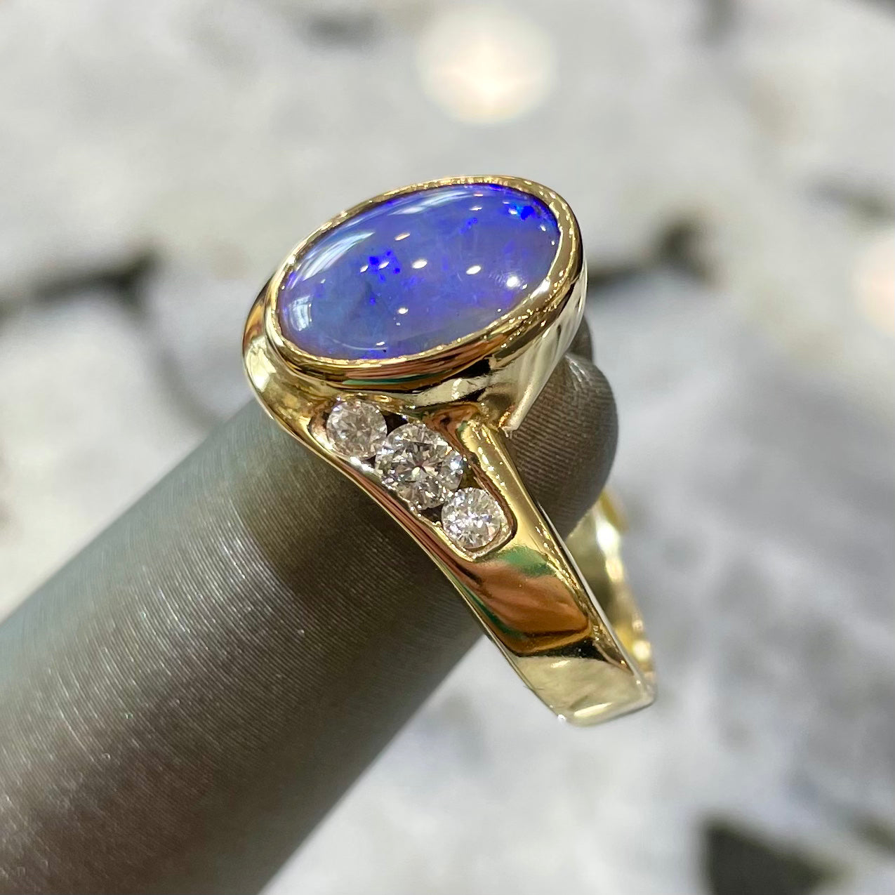 A yellow gold ring set with diamonds and a Lightning Ridge black opal from Australia.