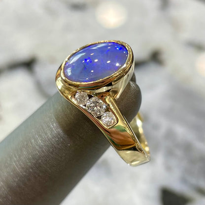 A yellow gold ring set with diamonds and a Lightning Ridge black opal from Australia.