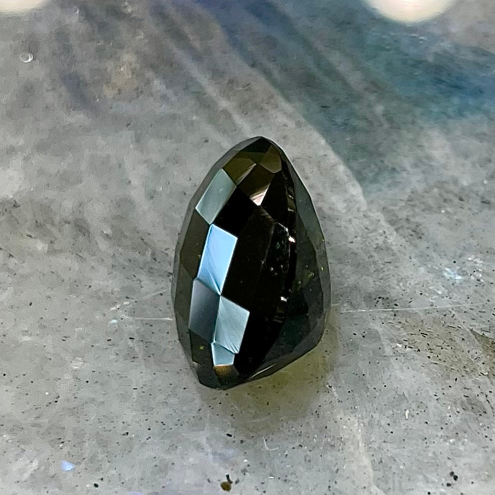 A loose faceted oval checkerboard cut moldavite stone.